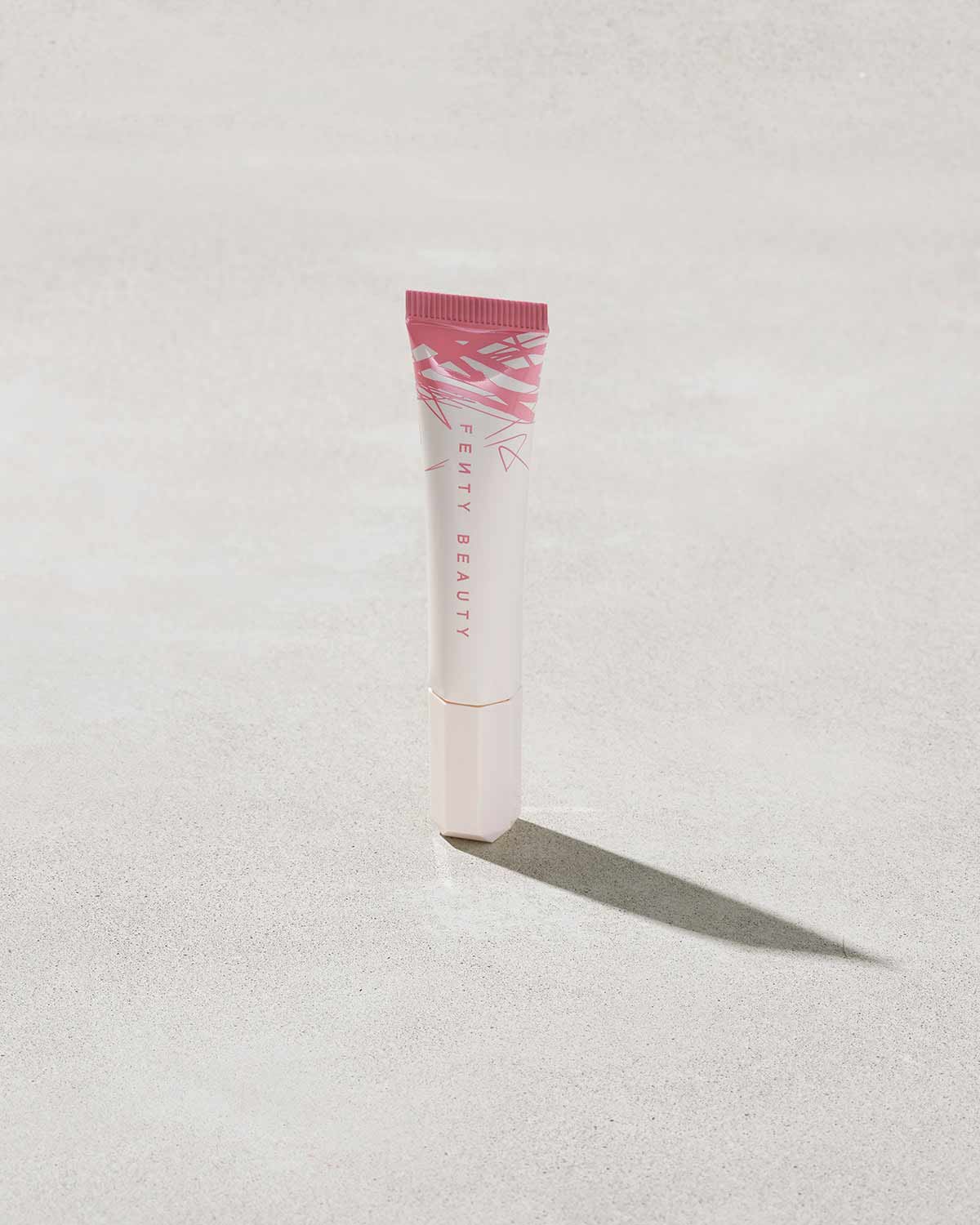 Closed Tube of Pro Kiss'r Luscious Lip Balm in shade Pinch Me on grey background.