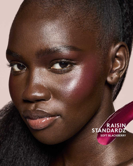 deep skin toned model wearing cheeks out freestyle cream blush in shade raisin standardz