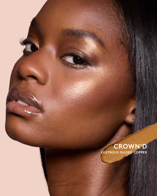 Deep skin toned model wearing match stix shimmer in shade crown'd.