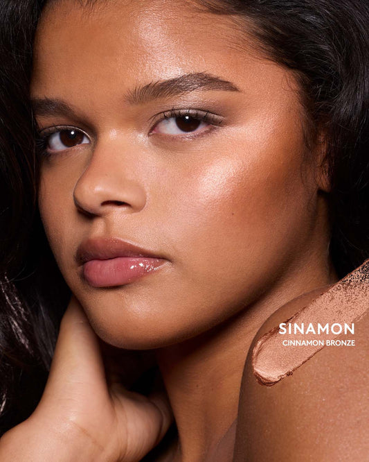 Medium-deep skin toned model wearing match stix shimmer in shade sinnamon.