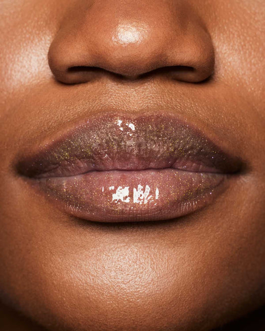 Product shot of Fenty Beauty Gloss Bomb Universal Lip Luminizer and packaging in limited edition Arcane collection shade Risky Ruling.