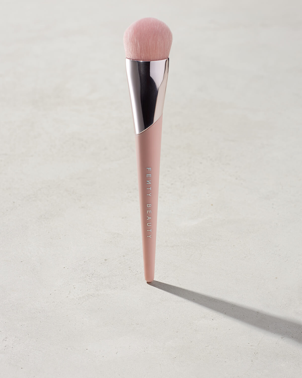 Full-Bodied Foundation Brush 110 standing upright on a concrete backdrop.