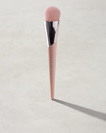 Full-Bodied Foundation Brush 110 standing upright on a concrete backdrop.