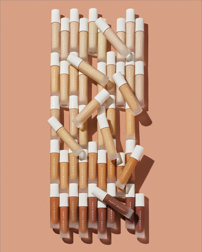 Editorial image of all 50 Pro Filt'r Soft Matte Longwear Foundation bottles laying on a peach background.
