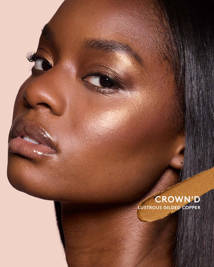 Deep skin toned model wearing match stix shimmer in shade crown'd.