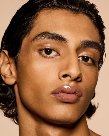 medium skin tone model wearing Gloss Bomb Heat Universal Lip Luminizer + Plumper in shade Fenty Glow Heat