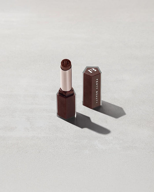 Open product shot of Gloss Bomb Stix Shimmer in shade Hot Chocolit on a concrete background.