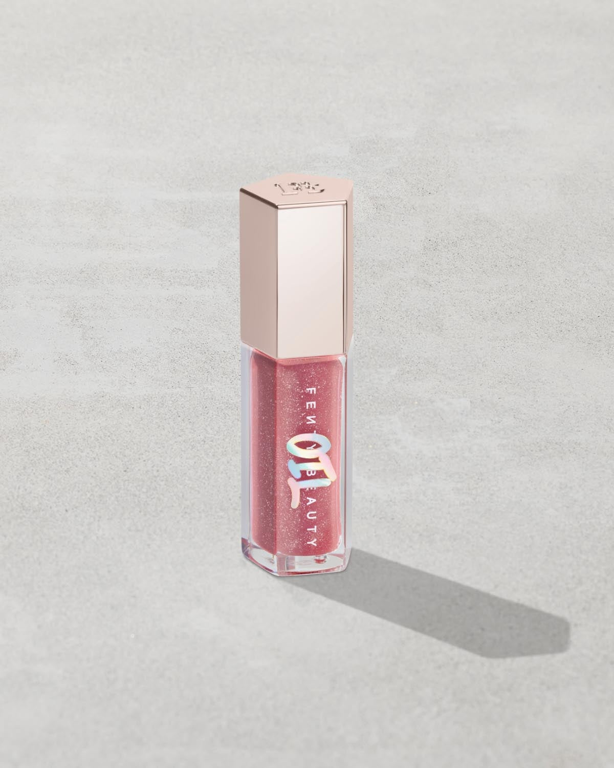 Gloss Bomb Oil Luminizing Oil and Gloss in shade Fussy product against a concrete background.