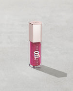Gloss Bomb Oil Luminizing Oil and Gloss in shade Raspberry Jams product against a concrete background.