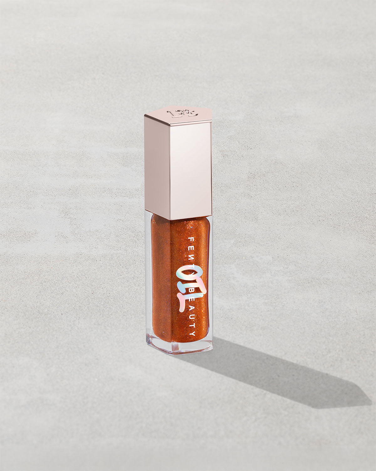 Gloss Bomb Oil Luminizing Oil and Gloss in shade Frosted Buns product against a concrete background.