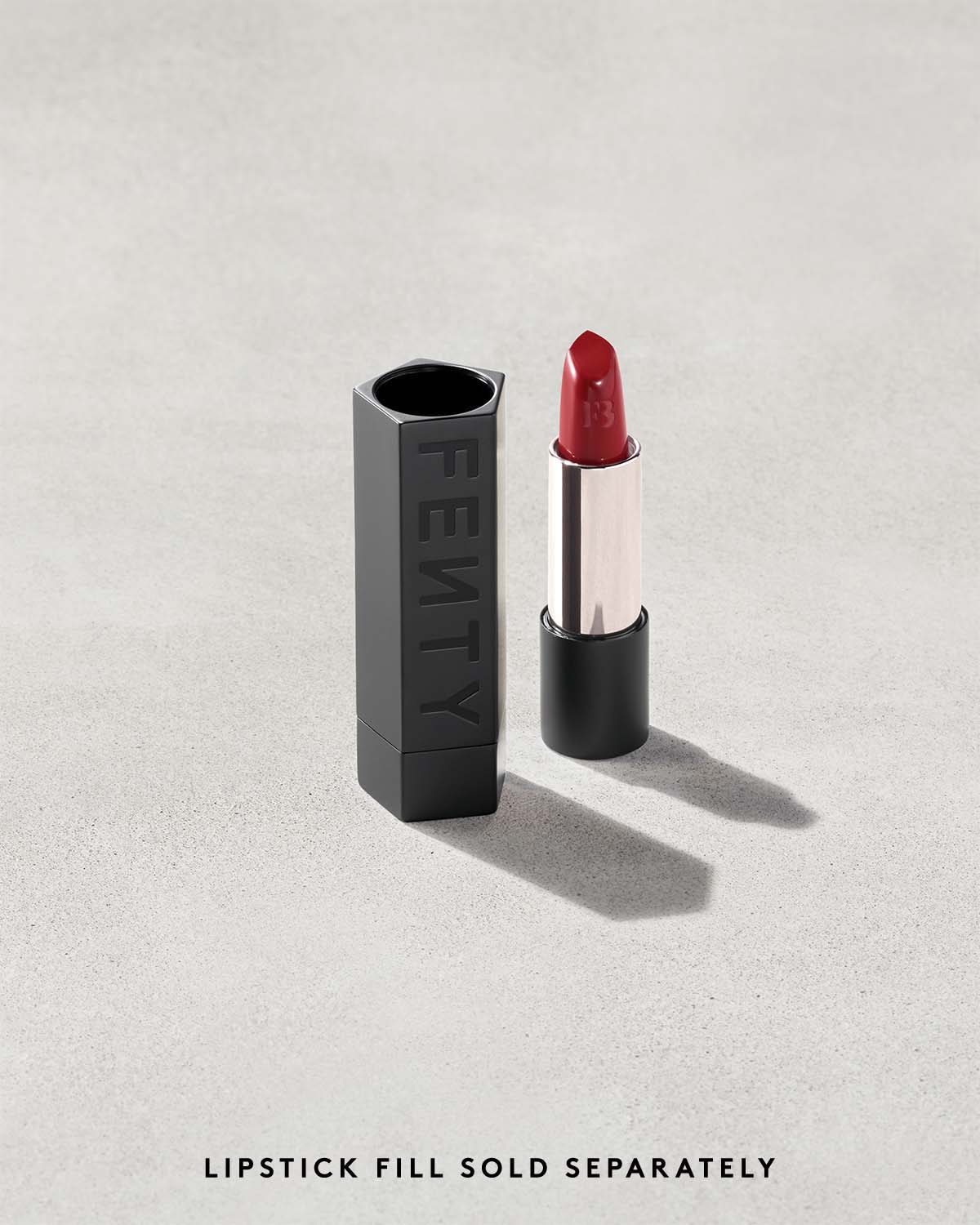 An open Fenty Icon refillable lipstick next to a lipstick case in matte black.