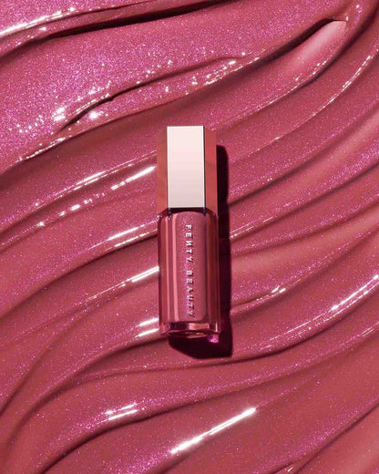 A closed tube of Gloss Bomb Universal Lip Luminizer with the lip gloss texture in the background.