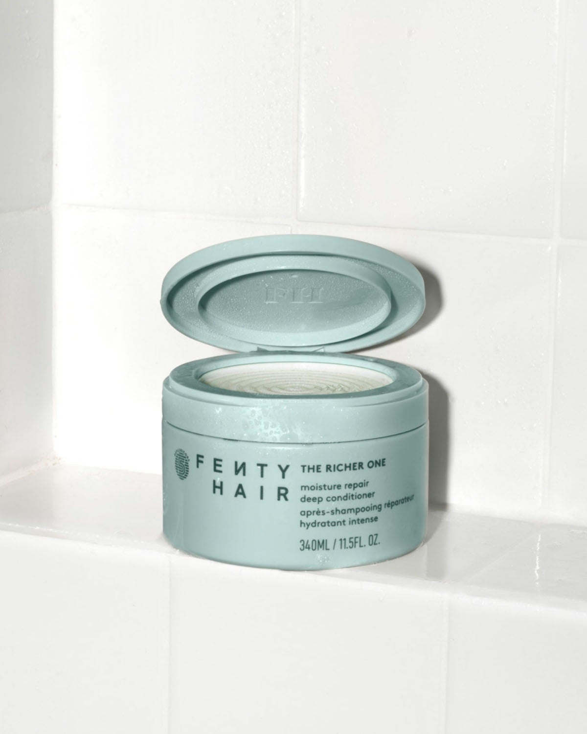 Fenty Hair The Richer One Moisture Repair Deep Conditioner tub made of 50% post-consumer recycled plastic in the shower.