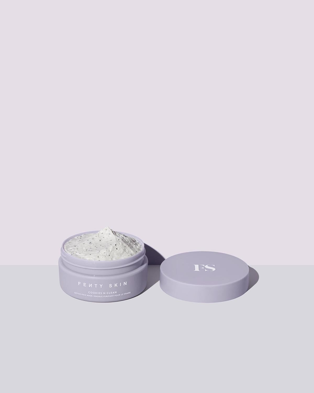 Open container of Cookies N Clean Clay Face Mask on a lilac background.
