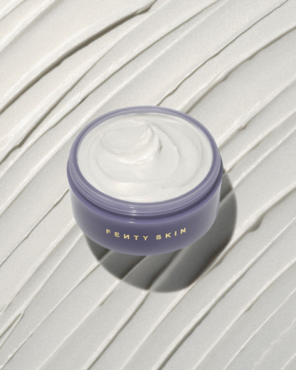An open tub of Butta Drop Shimmering Whipped Oil Body Cream with Tropical Oils + Shea Butter on a textured smear background.