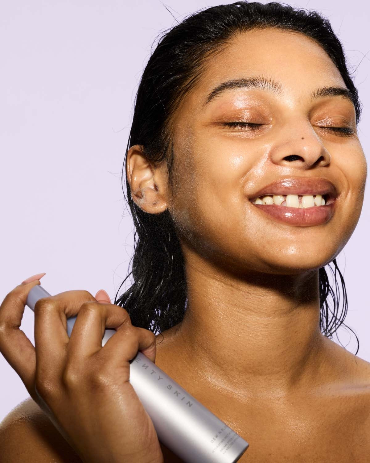 Woman applying face mist to her face with a white background