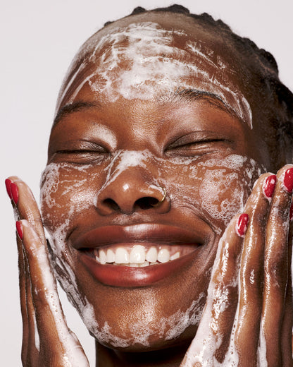 deep skin toned model washing face with cherry dub gel cleanser with a plush lather